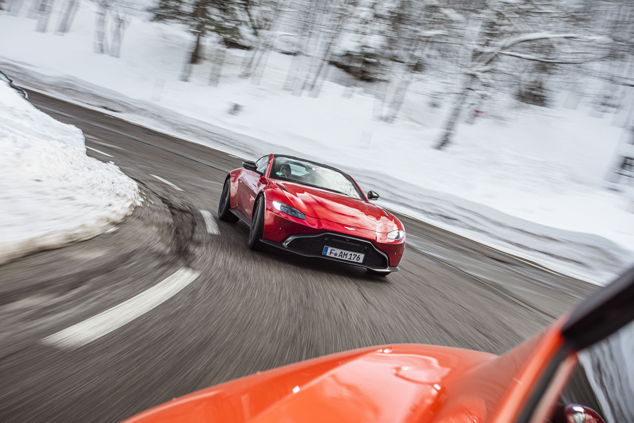 Roter Aston Martin Geneva bei Schnee in einer Kurve